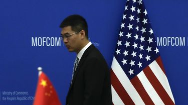 ARCHIVO - Un funcionario chino camina frente a las banderas de China y EEUU antes de una reunión entre la secretaria de Comercio estadounidense Gina Raimondo y su homólogo chino Wang Wentao, en el Ministerio de Comercio, en Beijing, el 28 de agosto de 2023. (AP Foto/Andy Wong, Pool, archivo)