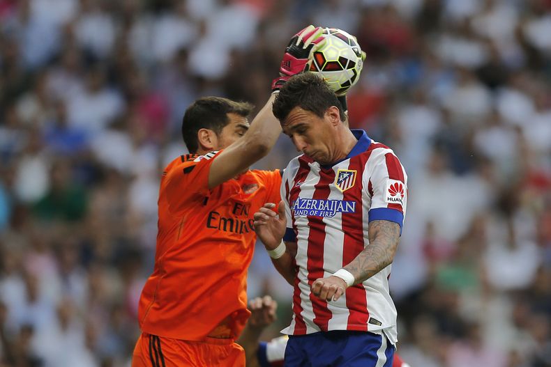 El arquero de Real Madrids Iker Casillas ataja ante la embestida de Mario Manduzic del Atl&eacute;tico Madrid en Madrie el 13 de septiembre del 2014. (AP Foto/Daniel Ochoa de Olza)