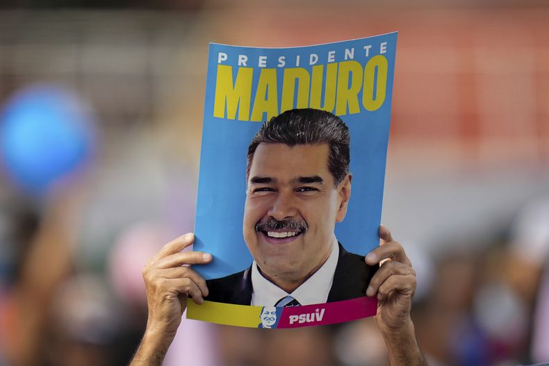 ARCHIVO - Un partidario muestra un cartel del presidente Nicolás Maduro durante su mitin de cierre de campaña electoral en Caracas, Venezuela, el 25 de julio de 2024. (AP Foto/Fernando Vergara, Archivo)