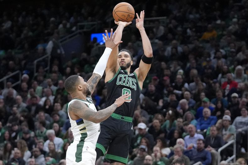 El alero de los Celtics de Boston Jayson Tatum lanza el balón sobre el base de los Bucks de Milwaukee Damian Lillard en el encuentro de la NBA del miércoles 20 de marzo del 2024. (AP Foto/Steven Senne)