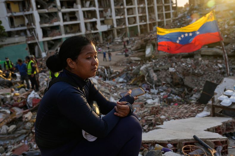 Estefany Landaez permanece sentada entre los escombros de un edificio esperando encontrar a sus dos hijos tras los terremotos en La Guaira, Venezuela, el domingo 12 de julio de 2026. (AP Foto/Ariana Cubillos)