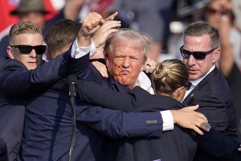El candidato republicano a la presidencia Donald Trump alza el puño mientras recibe ayuda para salir del escenario en un acto de campaña en Butler, Pensilvania, el sábado 13 de julio de 2024. (AP Foto/Gene J. Puskar)