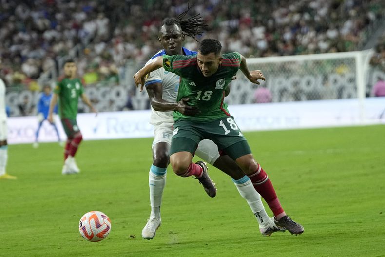 El mexicano Luis Chávez empujado por detrás por el hondureño Alberth Elis en el primer encuentro de la Copa Oro el domingo 25 de junio del 2023 en Houston. (AP Foto/David J. Phillip)