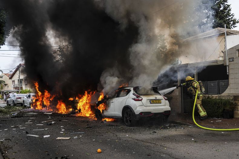 Bomberos israelíes extinguen un incendio en un lugar alcanzado por proyectiles disparados desde la Franja de Gaza, en Ashkelon, en el sur de Israel, el 9 de octubre de 2023. (AP Foto/Tsafrir Abayov)