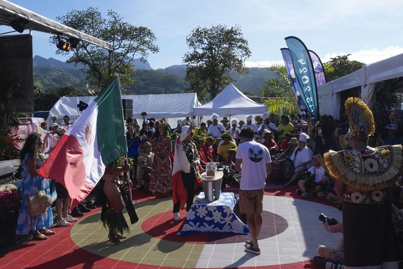 El mexicano Alan Cleland Quiñónez deposita arena de una playa de su país en una embarcación durante la ceremonia inaugural de los Juegos Olímpicos de 2024, en Papara, Tahití, el viernes 26 de julio de 2024 (AP Foto/Gregory Bull)