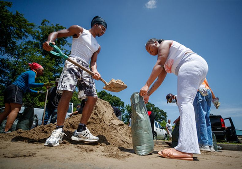 Christian Mosley-Richardson (izquierda) ayuda a Johnisha West a llenar sacos de arena antes de la llegada de la tormenta tropical Bertha, en Morris FX Jeff Sr. Park en Algiers, Nueva Orleans, el 20 de julio de 2026. (David Grunfeld/The Times-Picayune/The New Orleans Advocate via AP)