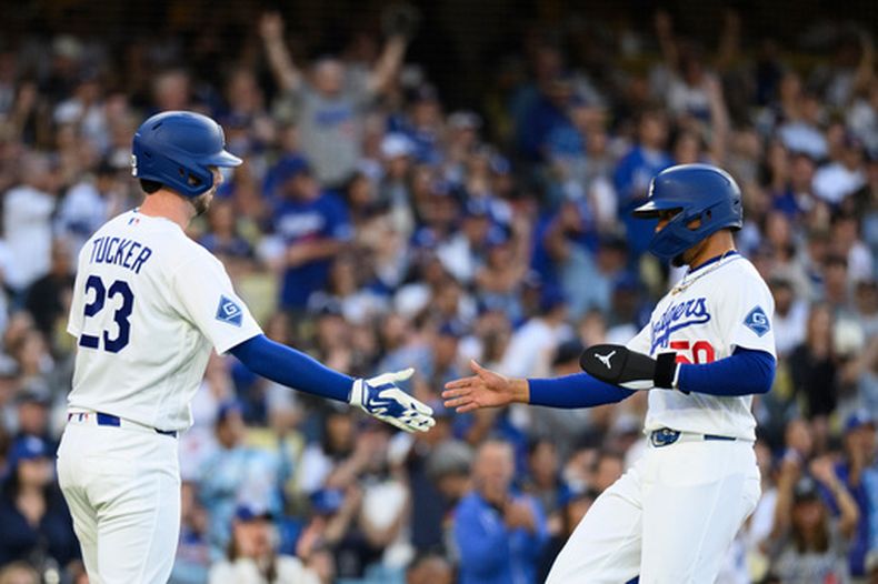Mookie Betts (derecha), de los Dodgers de Los Ángeles, celebra con Kyle Tucker (izquierda) tras anotar gracias a un sencillo productor de dos carreras de Max Muncy durante la primera entrada de un partido de béisbol contra los Orioles de Baltimore en Los Ángeles, el viernes 19 de junio de 2026. (Foto AP/Kyusung Gong)