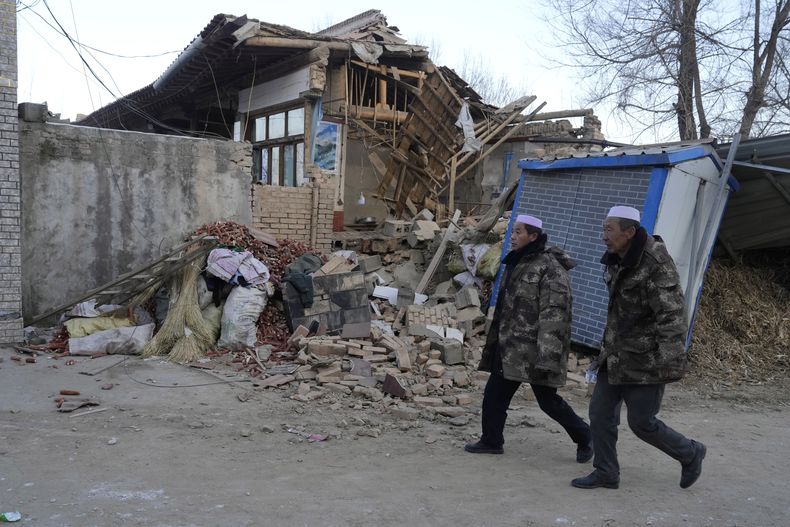 Residentes caminan el miércoles 20 de diciembre de 2023 frente a una vivienda colapsada tras un sismo en la localidad de Yangwa, en la provincia de Gansú, China. (AP Foto/Ng Han Guan)