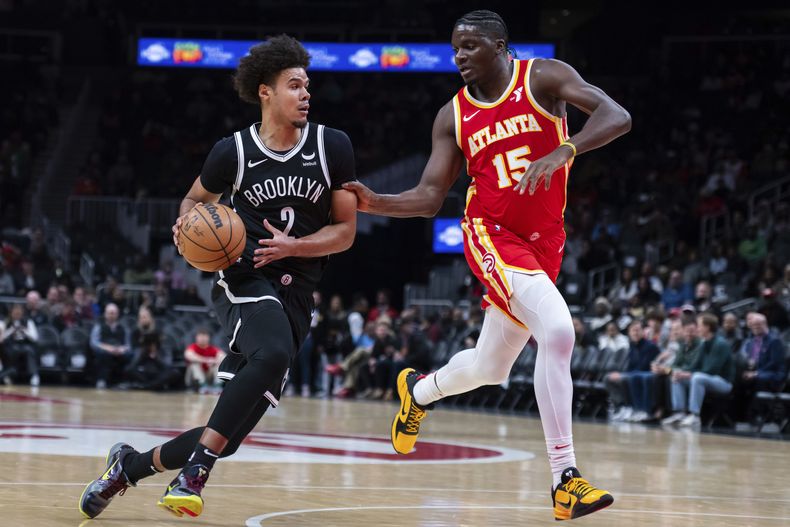 El pívot de los Nets de Brooklyn Cameron Johnson avanza hacia la canasta mientras lo defiende el pívot de los Hawks de Atlanta Clint Capela en el encuentro de la NBA el miércoles 6 de diciembre del 2023. (AP Foto/Hakim Wright Sr.)