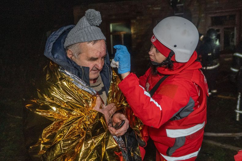Un paramédico presta primeros auxilios a un vecino herido en un ataque aéreo ruso en Járkiv, Ucrania, la noche del domingo 23 de noviembre de 2025. (AP Foto/Andrii Marienko)
