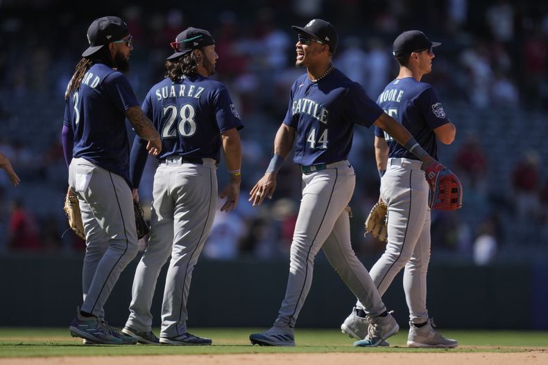 J.P. Crawford (3), Eugenio Suárez (28), Julio Rodríguez (44), y Dylan Moore (25) celebran el triunfo de los Marineros de Seattle sobre los Angelinos de Los Ángeles en Anaheim, California, el domingo 6 de agosto de 2023. (AP Foto/Ashley Landis)