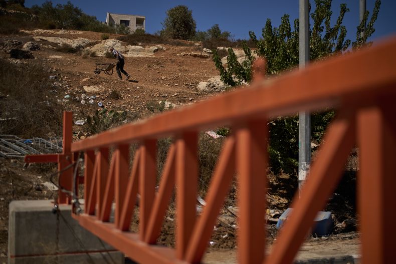 Un palestino empuja una carreta más allá de una barrera cerrada instalada por las autoridades israelíes para bloquear la entrada a la aldea de Sinjil, en Cisjordania, el 30 de septiembre de 2025. (AP Foto/Leo Correa)