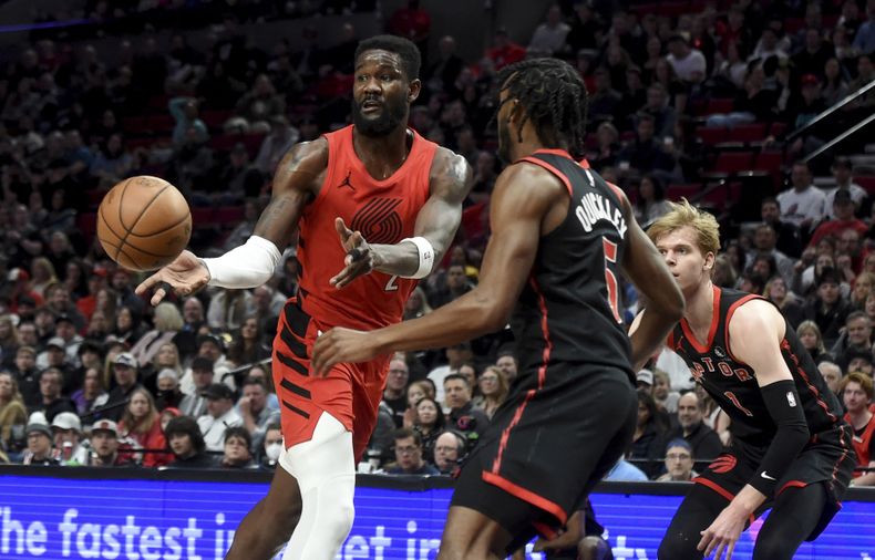 Deandre Ayton, pívot de los Trail Blazers de Portland, envía un pase frente a Immanuel Quickley de los Raptors de Toronto, el sábado 9 de marzo de 2024 (AP Foto/Steve Dykes)