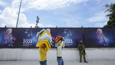 Dos trabajadores cargan butacas a ser instaladas en el Estadio Mágico González de San Salvador, el jueves 22 de junio de 2023, a un día de la inauguración de los Juegos Centroamericanos y del Caribe (AP Foto/Arnulfo Franco)