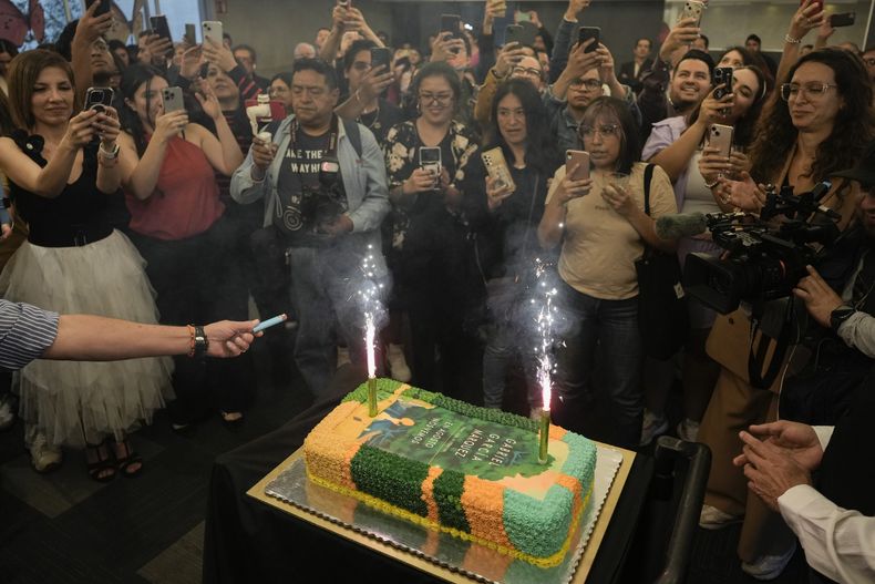 Personas reunidas alrededor de un pastel decorado con la portada de la novela En agosto nos vemos para celebrar el cumpleaños del autor colombiano Gabriel García Márquez y el lanzamiento de su novela póstuma en una librería en la Ciudad de México el miércoles 6 de marzo de 2024. (Foto AP/Eduardo Verdugo)