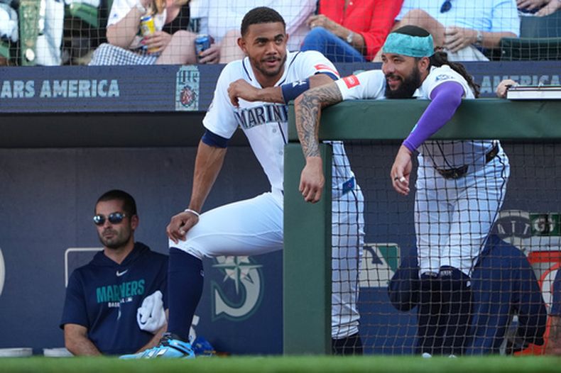 El bateador designado de los Marineros de Seattle, Julio Rodríguez, y J.P. Crawford conversan en el barandal de la banca durante la segunda entrada de un partido de béisbol contra los Gigantes de San Francisco, el sábado 18 de julio de 2026, en Seattle. (Foto AP/Lindsey Wasson)