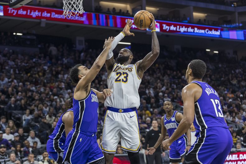 LeBron James, de los Lakers de Los Ángeles, encesta en bandeja frente a Trey Lyles, de los Kings de Sacramento, el sábado 21 de diciembre de 2024 (AP Foto/Sara Nevis)