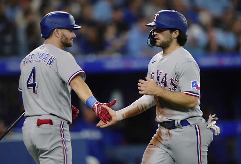 El campocorto de los Rangers Josh Smith celebra con Robbie Grossman tras anotar en la séptima entrada del encuentro ante los Azulejos el martes 12 de septiembre del 2023. (Nathan Denette/The Canadian Press via AP)
