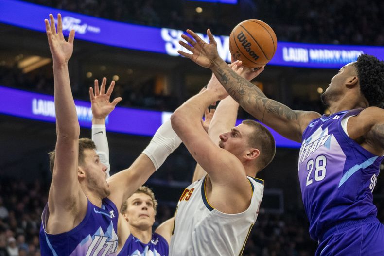 El pívot de los Nuggets de Denver Nikola Jokic lanza el balón mientras lo defienden Walker Kessler, Lauri Markkanen y Brice Sensabaugh del Jazz de Utah el lunes 30 de diciembre del 2024. (AP Foto/Rick Egan)