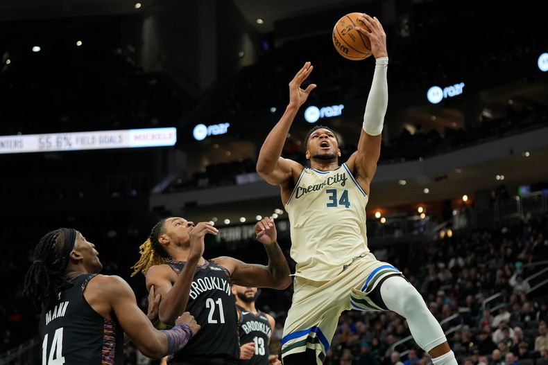 Giannis Antetokounmpo, de los Bucks de Milwaukee, dispara frente a Noah Clowney (21) y Terance Mann, de los Nets de Brooklyn, en el encuentro del sábado 29 de noviembre de 2025 (AP Photo/Aaron Gash)