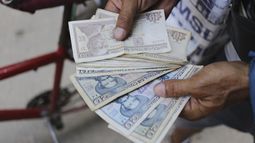 Un vendedor ambulante de helados muestra sus pesos cubanos, en La Habana, Cuba, el 20 de abril de 2024. Cada vez más cubanos tienen que lidiar con la escasez de dinero en efectivo en el país. Convertir esos pesos cubanos a otra moneda supone otro desafío debido a las varias y altamente fluctuantes tasas de intercambio en la isla. (AP Foto/Ariel Ley)