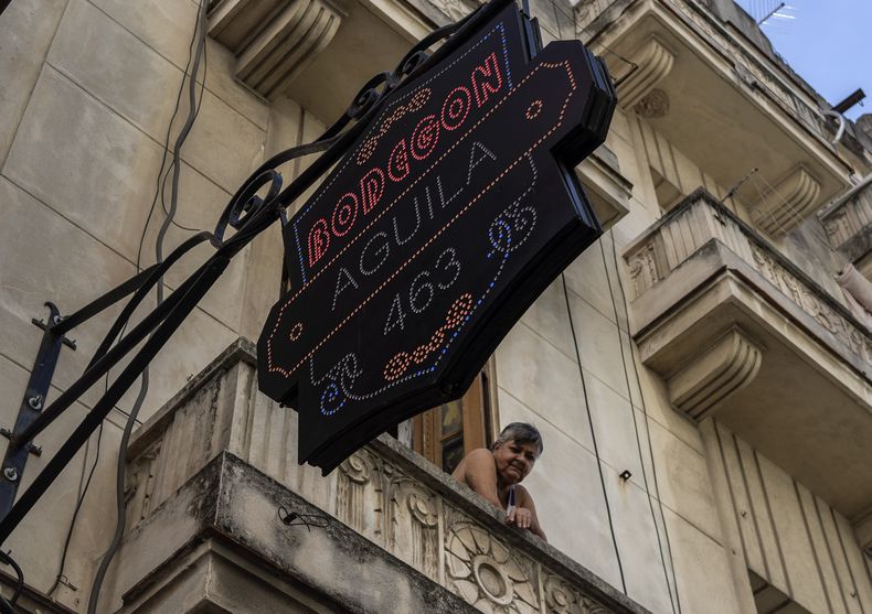 Una residente observa desde su balcón, sobre una tienda de comestibles privada en La Habana, Cuba, el 11 de noviembre de 2023. En los últimos meses, en toda la isla han surgido decenas de negocios bautizados como “mipymes”, que ofrecen verdaderos tesoros, aunque a precios elevados para la mayoría de la población. (AP Foto/Ramón Espinosa)