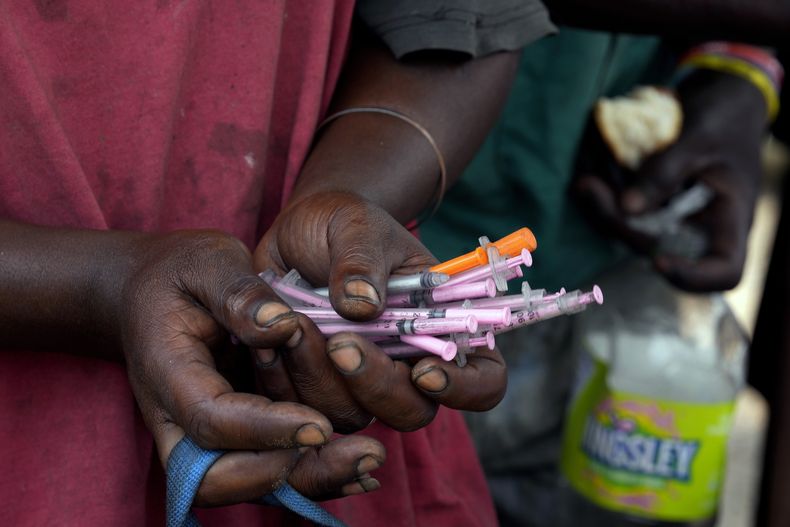 Una persona adicta a las drogas sostiene jeringas usadas en una carpa de un programa de intercambio en la que le darán algunas nuevas y estériles, el miércoles 5 de marzo de 2025, en Pretoria, Sudáfrica. (AP Foto/Themba Hadebe)
