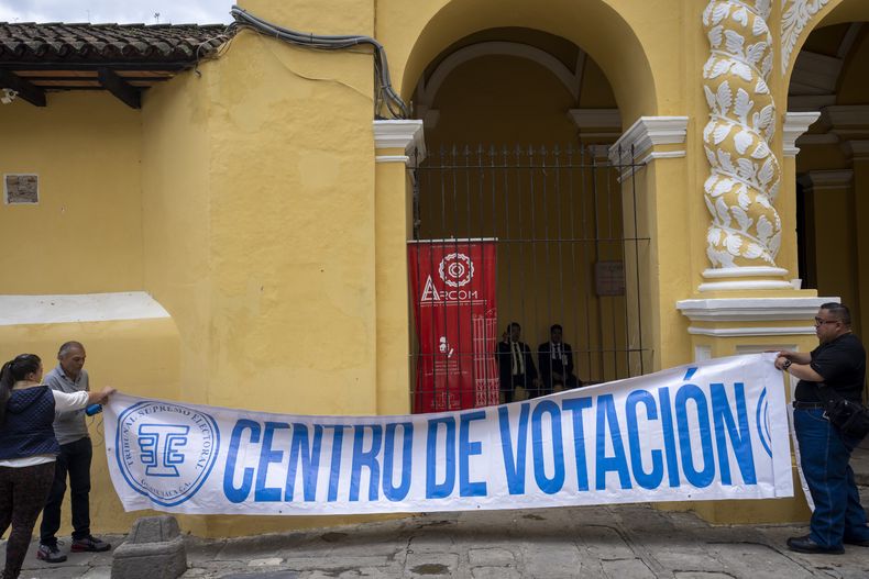 Los voluntarios cuelgan una pancarta con el mensaje centro de votación en la fachada de un colegio electoral, en Antigua, Guatemala, el sábado 24 de junio de 2023. Los guatemaltecos acuden a las urnas para elegir un nuevo presidente el 25 de junio. (Foto AP/Moisés Castillo)