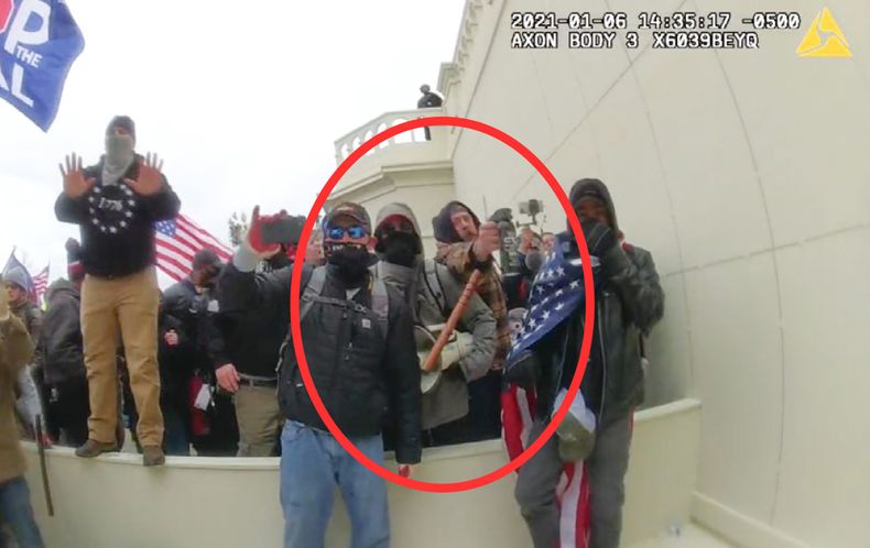 En esta imagen tomada por la cámara corporal de un policía de Washington, y difundida con anotaciones por el Departamento de Justicia, se ve a Peter Schwartz en el círculo rojo cuando usa un recipiente de aerosol pimienta contra policías el 6 de enero de 2021. (Departamento de Justicia vía AP)