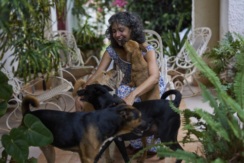 Bárbara Iglesias abraza a los perros callejeros que adoptó en el patio de su casa en La Habana, el miércoles 23 de julio de 2025. (AP Foto/Ramón Espinosa)