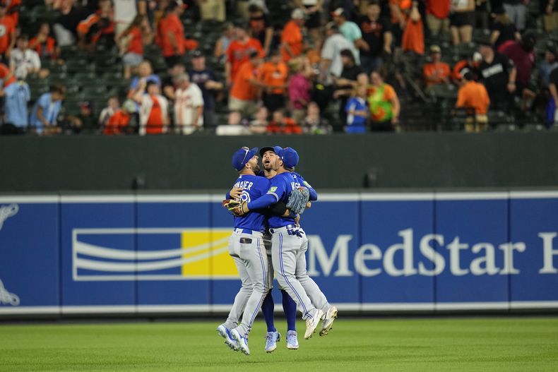 De izquierda a derecha, Kevin Kiermaier, George Springer y Daulton Varsho festejan la victoria de los Azulejos de Toronto sobre los Orioles de Baltimore, el martes 22 de agosto de 2023 (AP Foto/Julio Cortez)