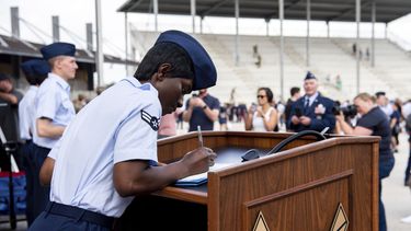 La aviadora de primera clase Delbrah Assamoi, de Costa de Marfil, firma su certificado de ciudadanía estadounidense al final de una ceremonia de entrenamiento militar básico en la Base Conjunta San Antonio-Lackland, el 26 de abril de 2023, en San Antonio, Texas. (Vanessa R. Adame/Fuerza Aérea de Estados Unidos vía AP)