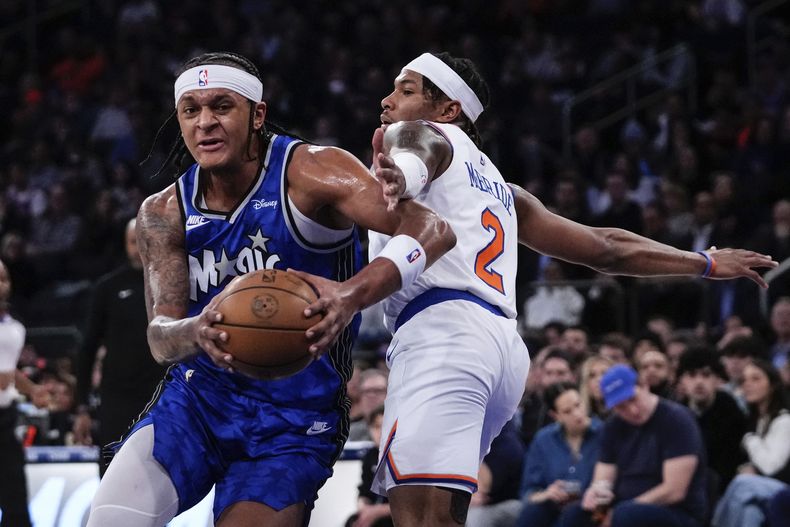 Paolo Banchero, izquierda, del Magic de Orlando, avanza rumbo a la canasta superando a Miles McBride (2), de los Knicks de Nueva York, durante la primera mitad del juego de baloncesto de la NBA, el lunes 15 de enero de 2024. (AP Foto/Frank Franklin II)