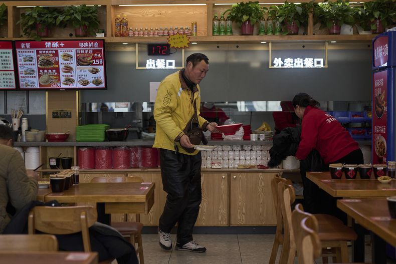 Un repartidor de comida de Meituan recoge su pedido en el restaurante Yushiji que ofrece alimentos con descuento, el 18 de marzo de 2025, en Beijing. (AP Foto/Andy Wong)