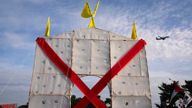 Un avión sobrevuela una estructura en forma de arco que levantaron los manifestantes en el Memorial Circle, en Arlington, Virginia, para protestar contra el proyecto del Arco del Triunfo, el jueves 1 de octubre de 2026. (AP Foto/Allison Robbert)