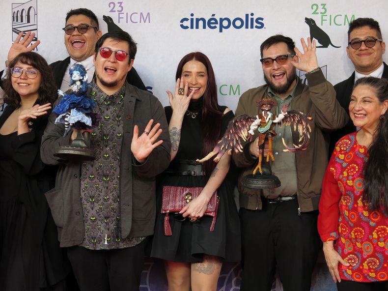 Los cineastas mexicanos Roy Ambriz, tercero desde la izquierda, y Arturo Ambriz, tercero desde la derecha, posan para una foto con la actriz y directora Mireya Mendoza, centro, en un evento de alfombra roja para la película Soy Frankelda en el Festival de Cine de Morelia, en Morelia, México, el sábado 12 de octubre de 2025. (Foto AP/Berenice Bautista)