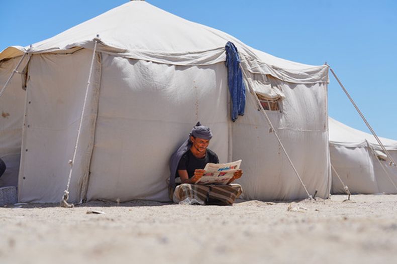 Un yemení desplazado lee un diario en el campamento de Al-Firdaws, en Ras Imran, en las afueras de Adén, Yemen, el 5 de octubre de 2026. (AP Foto/Abdulnasser Alseddik)