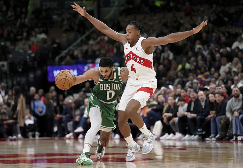 Jayson Tatum (0), de los Celtics de Boston, busca pasar a Scottie Barnes (4), de los Raptors de Toronto, durante la acción de pretemporada de la NBA en la segunda mitad en Toronto, el martes 15 de octubre de 2024. (Nathan Denette/The Canadian Press vía AP)