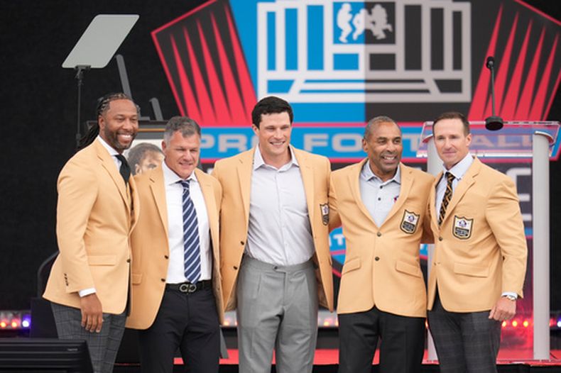 Los exjugadores de la NFL Larry Fitzgerald, Adam Vinatieri, Luke Kuechley, Roger Craig, y Drew Brees posan para una foto con sus sacos tras ingresar al Salón de la Fama del Fútbol Profesional el sábado 8 de agosto del 2026. (AP Foto/Sue Ogrocki)