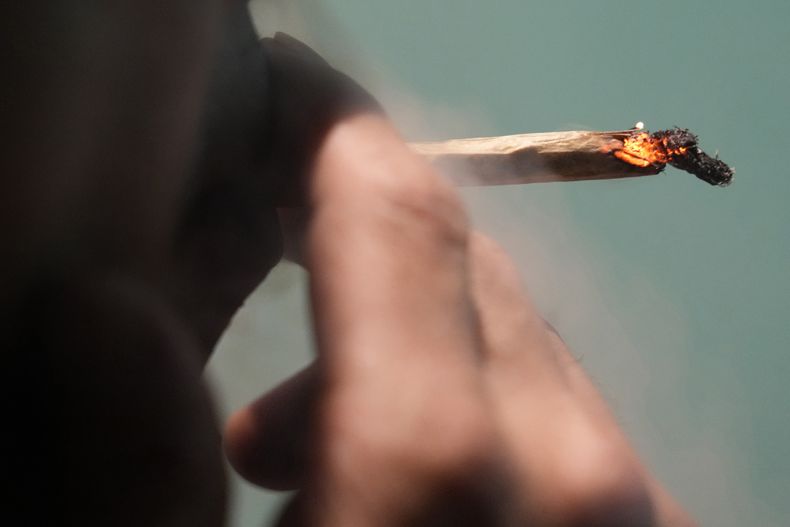 ARCHIVO - Un turista japonés fuma cannabis en una tienda holandesa en Bangkok, Tailandia, el 27 de junio de 2023. (Foto AP/Sakchai Lalit, archivo)