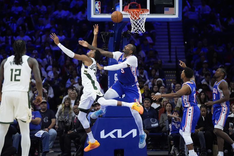 Giannis Antetokounmpo, de los Bucks de Milwaukee, a la izquierda, intenta lanzar un tiro que superó a Andre Drummond, de los 76ers de Filadelfia, durante la segunda mitad de un partido de baloncesto de la NBA, el miércoles 23 de octubre de 2024, en Filadelfia. (Foto AP/Matt Slocum)