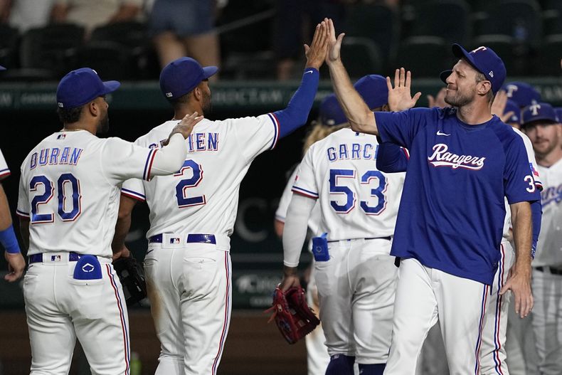 El dominicano Ezequiel Durán, Marcus Semien, el cubano Adolis García y Max Scherzer, de los Rangers de Texas, festejan la victoria por 2-0 sobre los Medias Blancas de Chicago, el martes 1 de agosto de 2023 (AP Foto/Tony Gutiérrez)