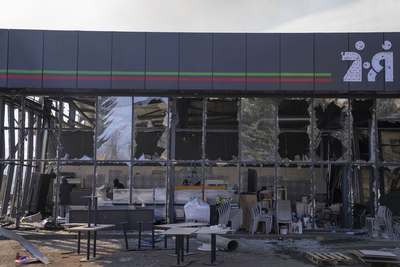 Ciudadanos realizan tareas de limpieza en una tienda que sufrió daños en un bombardeo ruso, en Kostantinovka, en la región de Donetsk, Ucrania, el domingo 25 de febrero de 2024. (AP Foto/Alex Babenko)