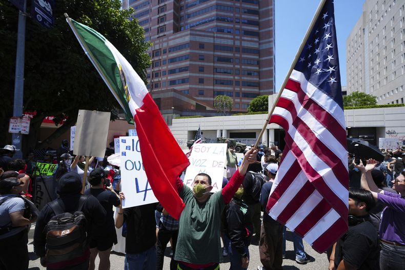 Un manifestante sostiene una bandera de México y una de Estados Unidos durante una protesta contra las redadas migratorias, el martes 10 de junio de 2025, en Los Ángeles. (AP Foto/Damian Dovarganes)