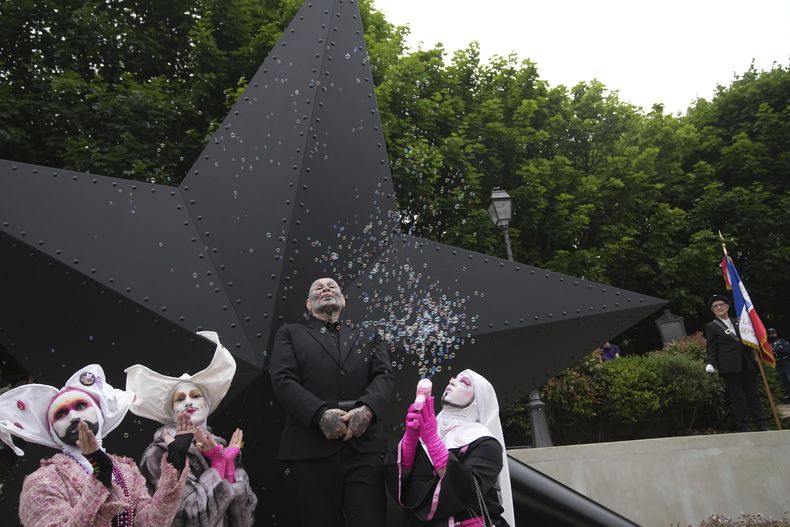 El artista francés Jean-Luc Verna, centro, posa con actores durante la inauguración de su escultura, un monumento a las víctimas del régimen nazi, largamente ignoradas, y a todas las personas LGBTQ+ perseguidas en la historia, en París, el sábado 17 de mayo de 2025. (AP Foto/Christophe Ena)