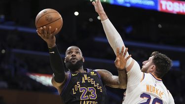 El alero de los Lakers de Los Ángeles LeBron James lanza el balón a la canasta mientras lo defiende el pívot de los Suns de Phoenix Jusuf Nurkic en el encuentro de la Copa de la NBA el martes 5 de diciembre del 2023. (AP Foto/Mark J. Terrill)