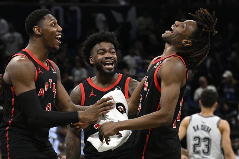 De izquierda a derecha, RJ Barrett, Jamal Shead y JaKobe Walter, de los Raptors de Toronto, festejan la victoria sobre el Magic de Orlando, el martes 4 de marzo de 2025 (AP Foto/Phelan M. Ebenhack)