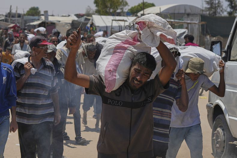 Un palestino carga un saco con comida y ayuda humanitaria distribuida por la Fundación Humanitaria de Gaza, una organización respaldada por Estados Unidos, en Rafah, en el sur de la Franja, el 11 de junio de 2025. (AP Foto/Abdel Kareem Hana)