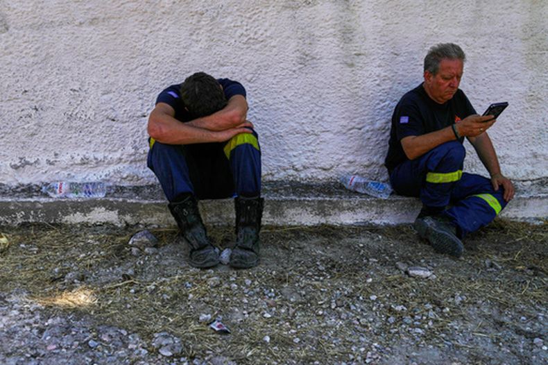 Bomberos descansan un día después de un incendio forestal en el pueblo de Peristeria, al oeste de Atenas, Grecia, lunes 17 de agosto de 2026. (Foto AP/Thanassis Stavrakis)