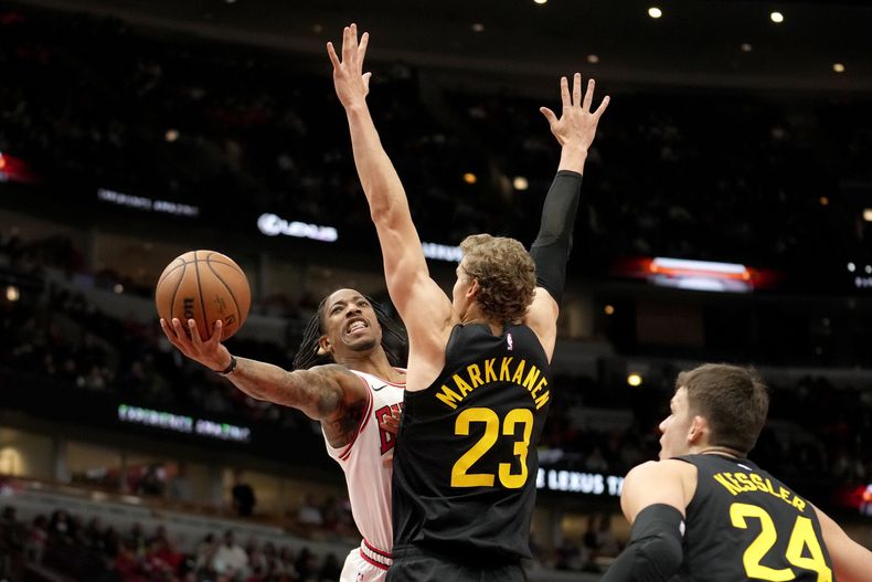 DeMar DeRozan, de los Bulls de Chicago, lanza ante Lauri Markkanen, del Jazz de Utah, ante la mirada Walker Kessler, en la primera mitad del juego de la NBA que enfrentó a ambos equipos, el 6 de noviembre de 2023, en Chicago. (AP Foto/Charles Rex Arbogast)